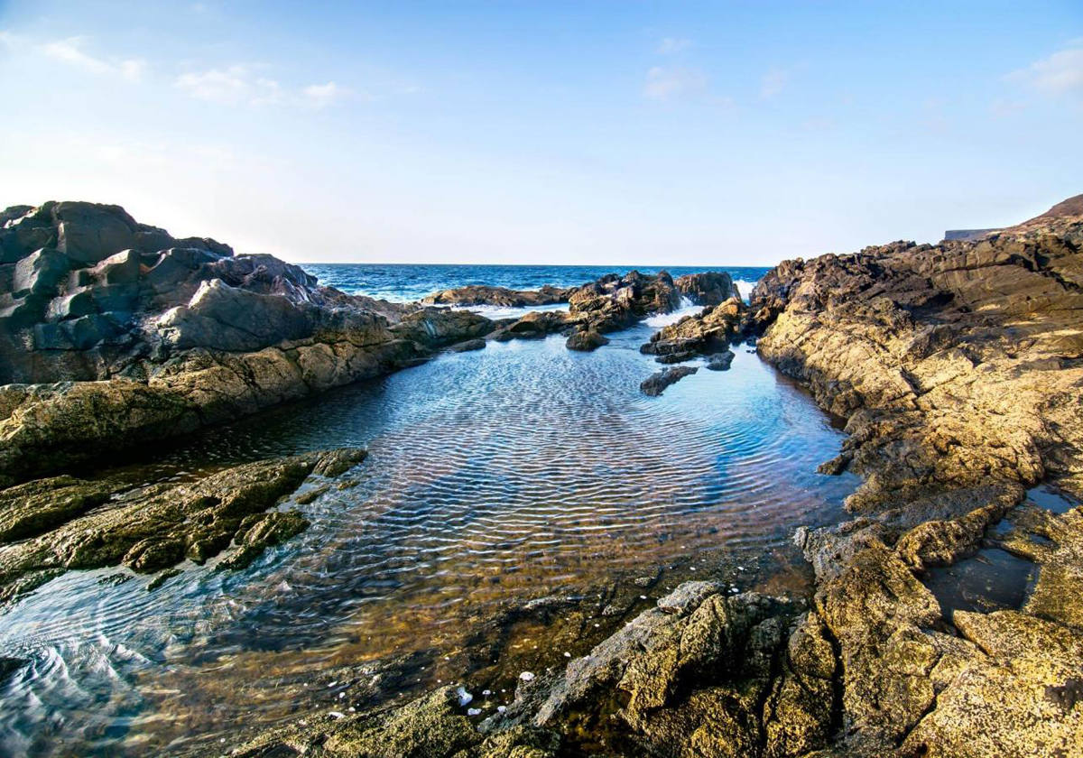 Un baño alternativo y relajante en Fuerteventura.- Fuerteventura es sinónimo de playas infinitas de fina arena rubia. Sin embargo, su costa oeste, de oleaje más bravío, esconde tesoros de irrenunciable visita si se busca el contraste. Aguas Verdes, en Betancuria, es uno de ellos y resume a la perfección la amplia oferta de piscinas naturales vírgenes de las Islas Canarias. Unos seis kilómetros se ven salpicados por charcos y entrantes de mar dignos de una visita si la prioridad es el relax y el aislamiento sin huellas humanas.