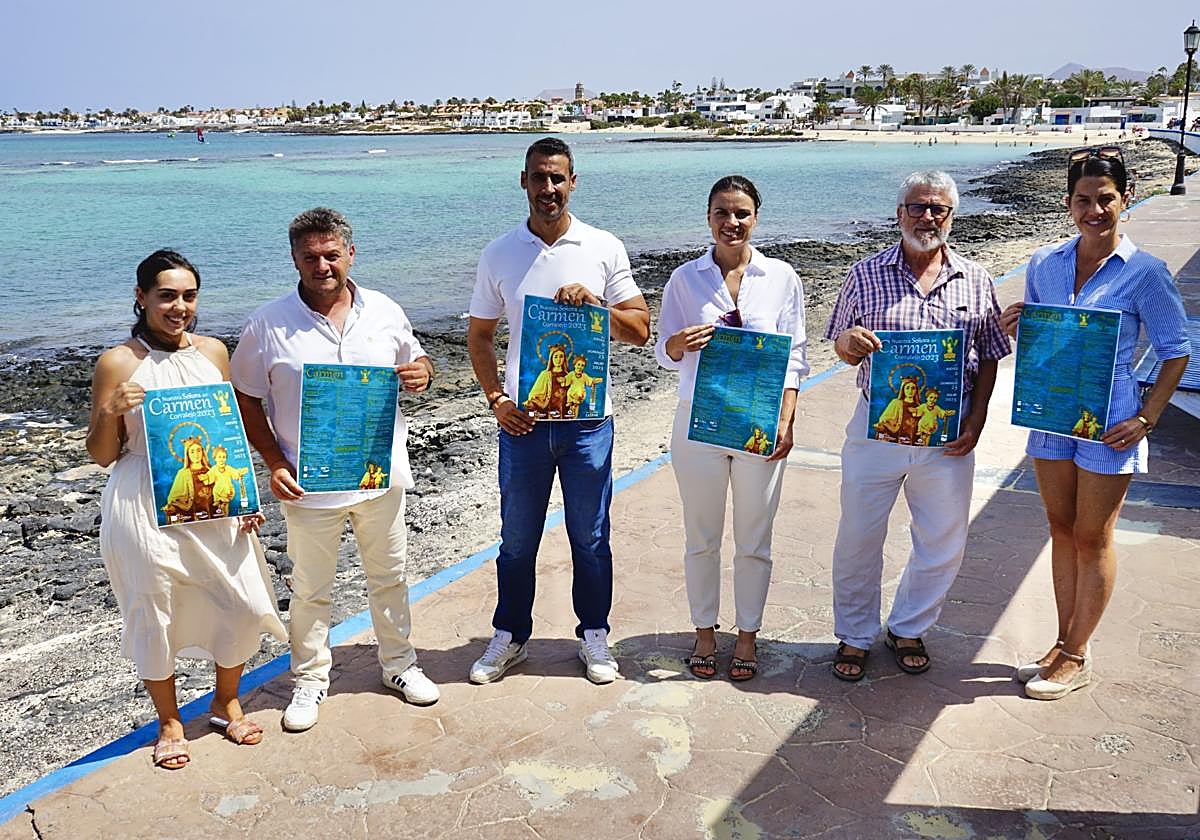 El alcalde Isaí Blanco y otros concejales, más Tinín Martínez, director de la agrupación folclórica Dunas de Corralejo, en el paseo marítimo con el cartel de las fiestas.