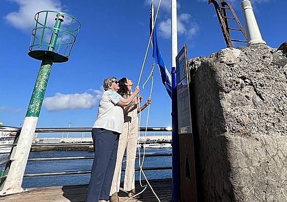 La concejala Sara Perdomo, y la vecina Nieves Ramos izan la bandera azul en Las Nieves.