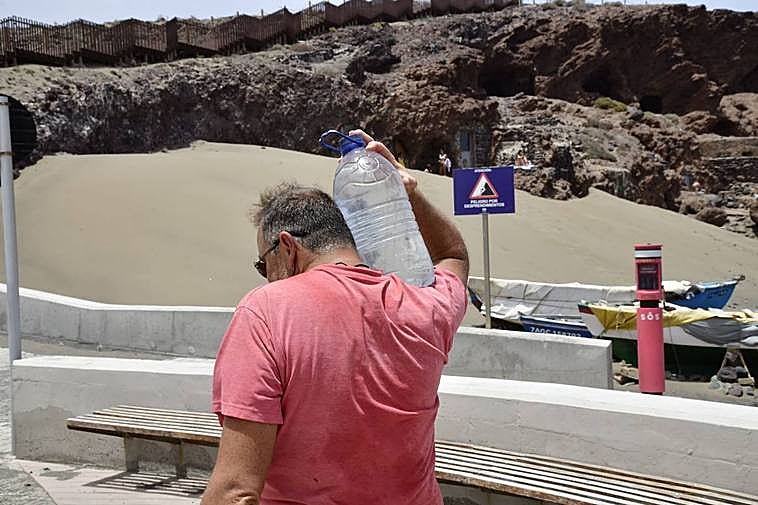 En la imagen, un hombre carga con una garrafa de agua para ayudar a los lagartos de El Burrero a superar la ola de calor.