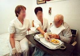 Dos auxiliares prestan atención a domicilio para tareas básicas a una persona dependiente.