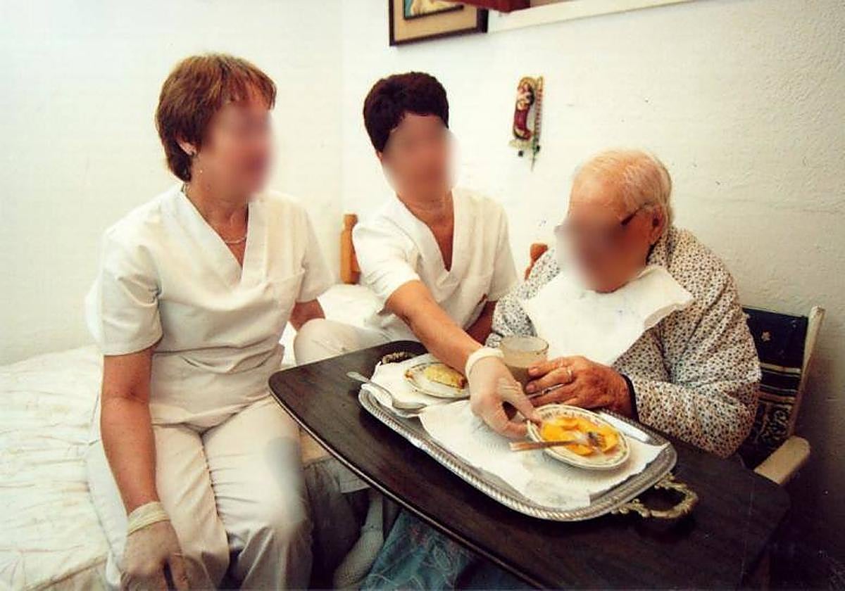 Dos auxiliares prestan atención a domicilio para tareas básicas a una persona dependiente.