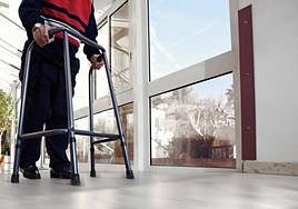 Un mayor dependiente avanza por el pasillo de una residencia.