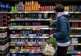 Un consumidor revisa la información nutricional de una bebida energética en un supermerdo.