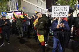 Un señor con un paraguas y una pancarta en la que llama fascista al líder del Partido Socialista, Pedro Sánchez, junto a otros particulares con banderas de España.