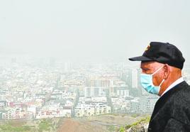 Un hombre con mascarilla observa unas vistas de la capital gran canaria durante un episodio de calima este año.