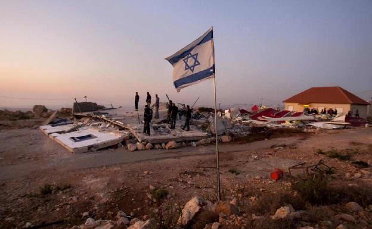 Colonos israelíes sobre las ruinas de una casa demolida en un asentamiento pasado 