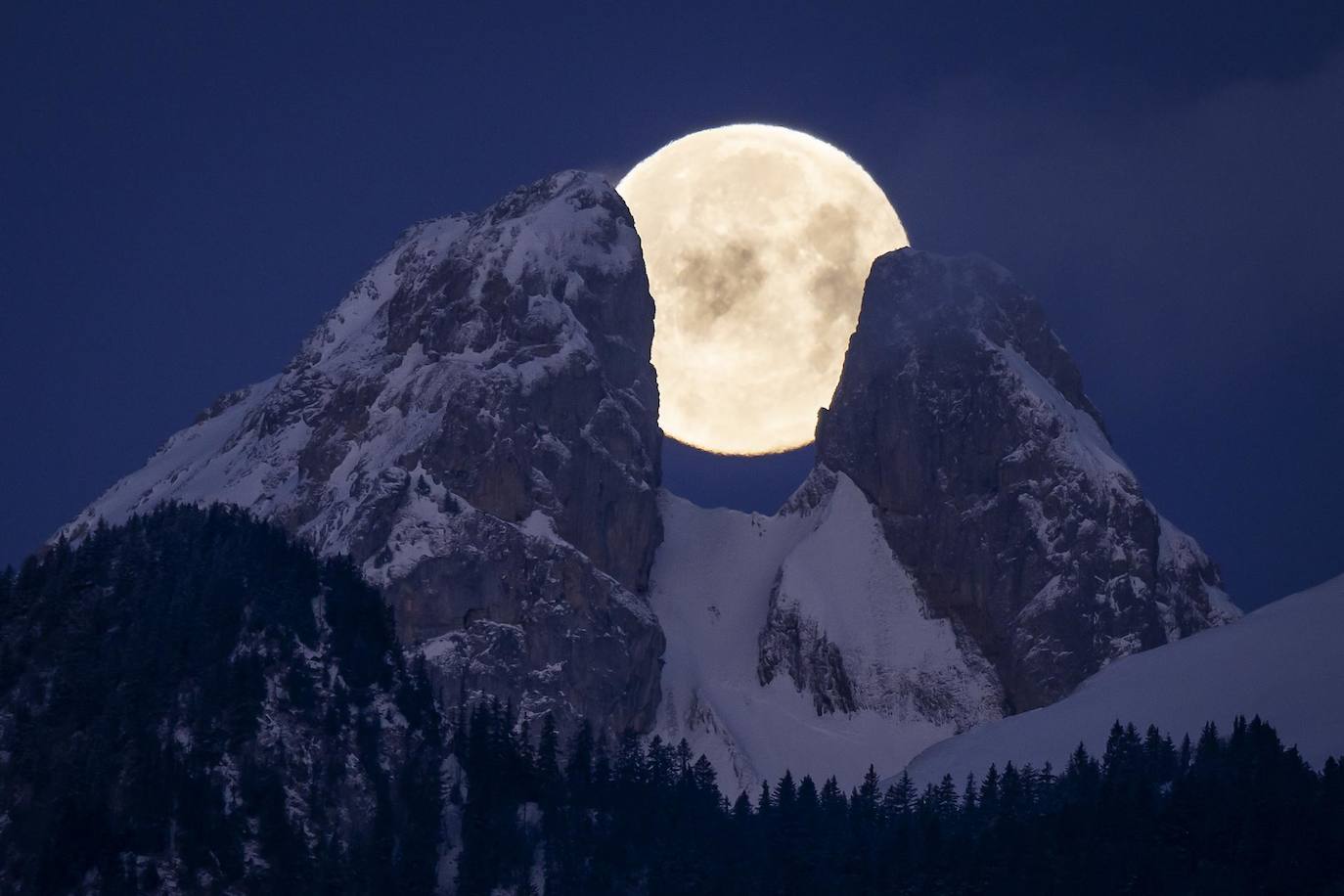 La luna llena se pone detrás del pico de la montaña Les Jumelles en Aigle (Suiza).- La luna llena se oculta detrás de las montañas, incluidos los picos gemelos de Les Jumelles en el Chablais Valaisan, visto desde Aigle, Suiza.