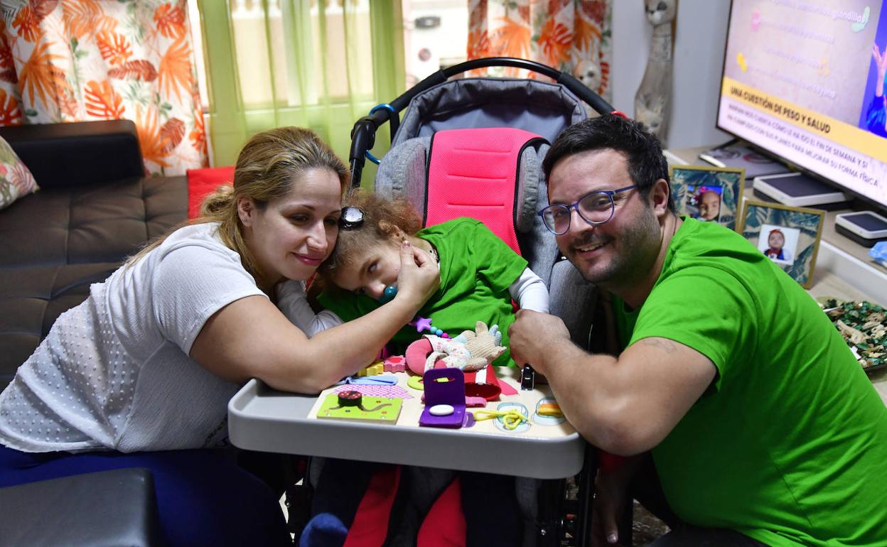 Cathaysa y Aridañy se abrazan a su niña, Marta. 