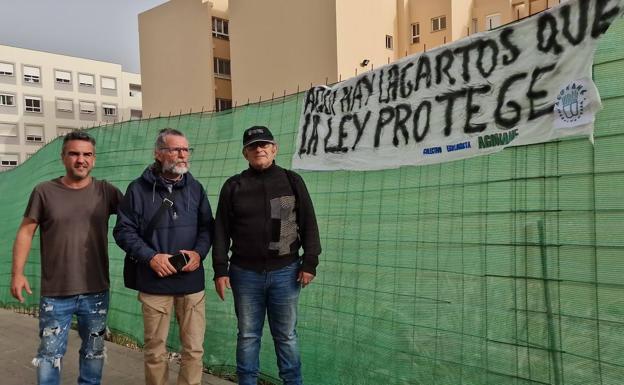 Honorio Galindo -izquierda- y otros dos ciudadanos ante un cartel que colocaron en la valla de obra. 