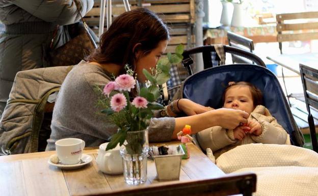 Una madre atendiendo a su bebé en una cafetería.