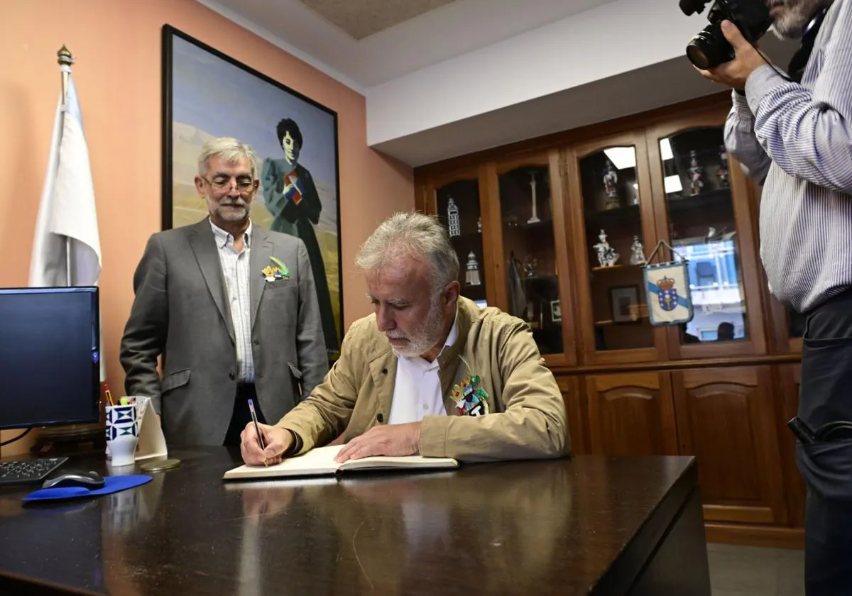 Torres firma en el libro de honor de la Casa de Galicia ante su presidente, Albino Aneiros.