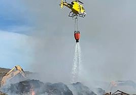 Un helicóptero del GES descarga agua sobre las montañas de material de la planta de compostaje de Parue La Reina, en el municipio de Arona.
