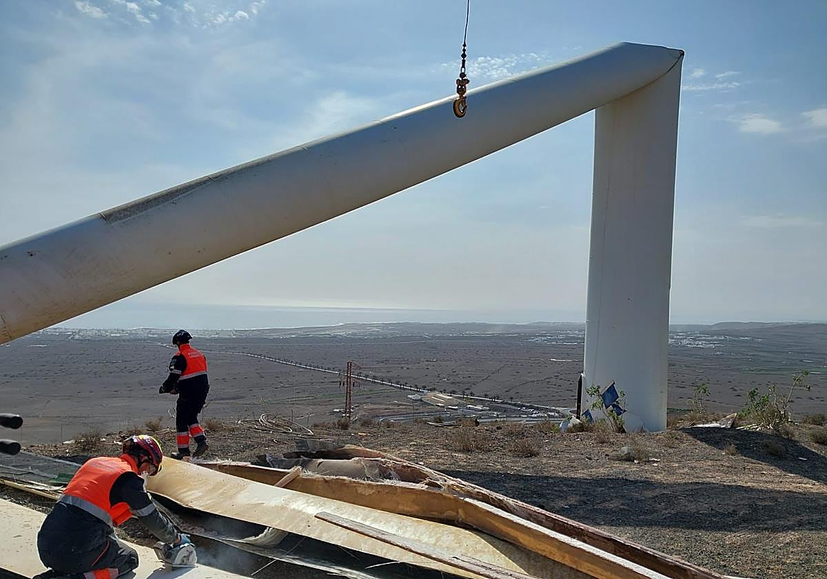 Bomberos retirarando parte del aerogenerador roto el martes.