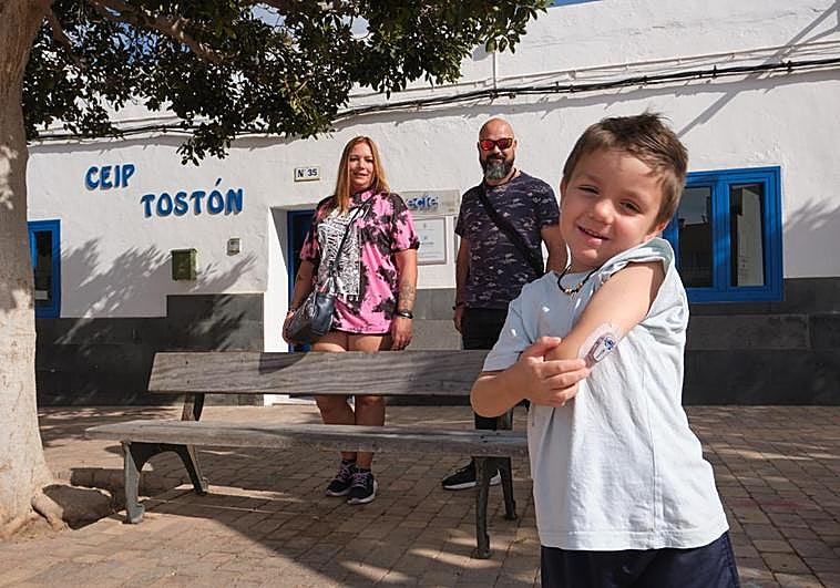 Eiden enseña su sensor de glucemia en presencia de sus padres, Laia y Harold, a la puerta del CEIP El Tostón, en El Cotillo, en el municipio de La Oliva.