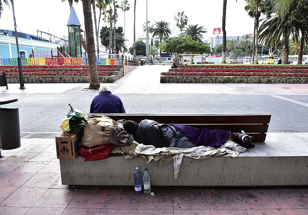 Una persona sin hogar duerme en un banco de Santa Catalina, en Las Palmas de Gran Canaria.