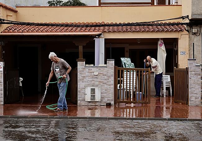 Vecinos de Pozo Izquierdo limpiando los patios de sus viviendas tras las lluvias.
