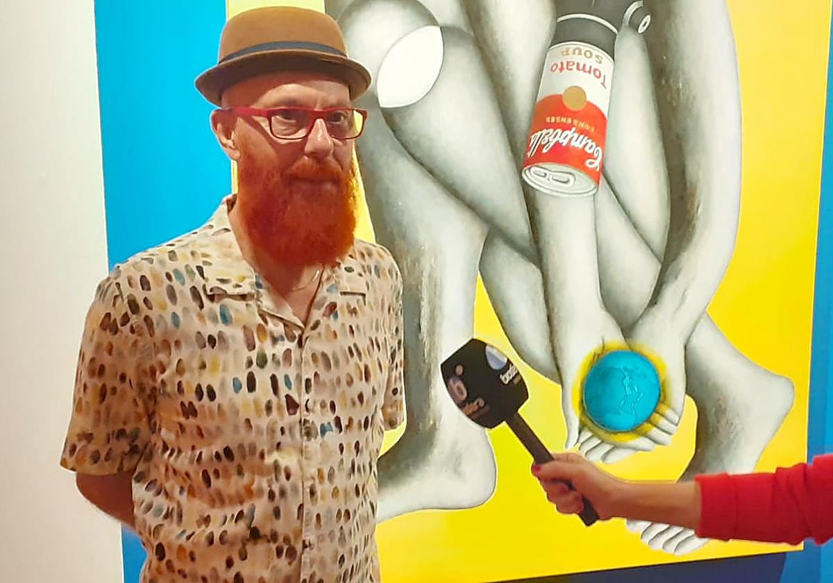 Artista siendo entrevistado ante una de sus obras.