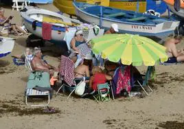 Un grupo de personas se apelotona bajo una sombrilla en la playa de Las Canteras.