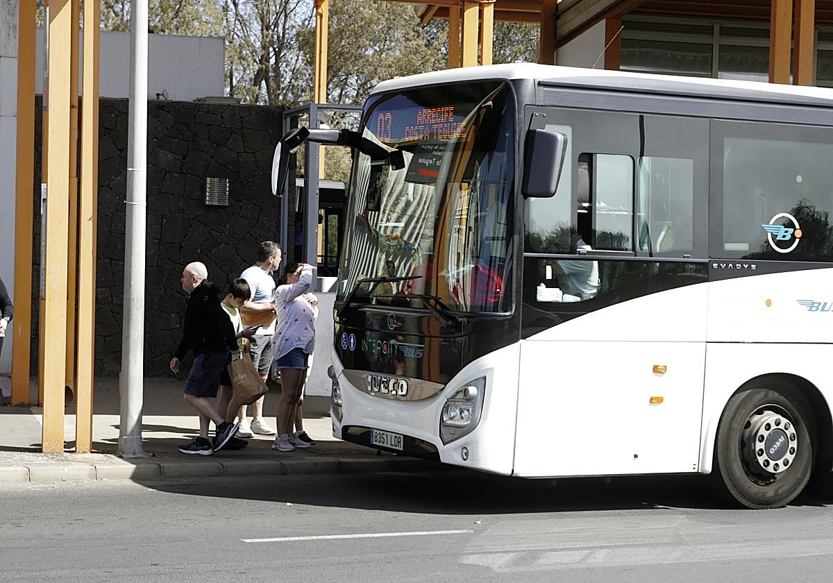 Guagua interurbana operando en el intercambiador Arrecife, con viajeros en espera.