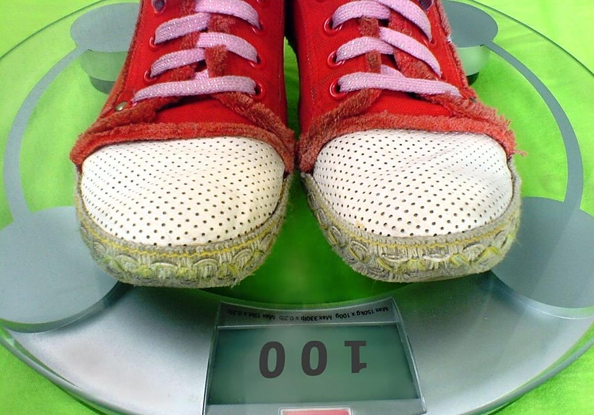 Imagen de un niño pesándose en una vascula.