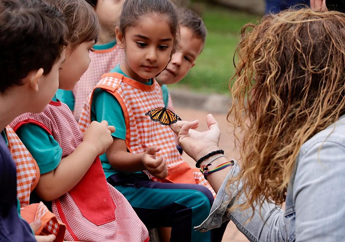 La concejala Gemma Martínez Soliño sostiene una monarca ante la mirada de los alumnos del CEIP Don Benito.