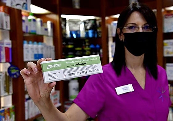 Una boticaria muestra un test de antígenos.