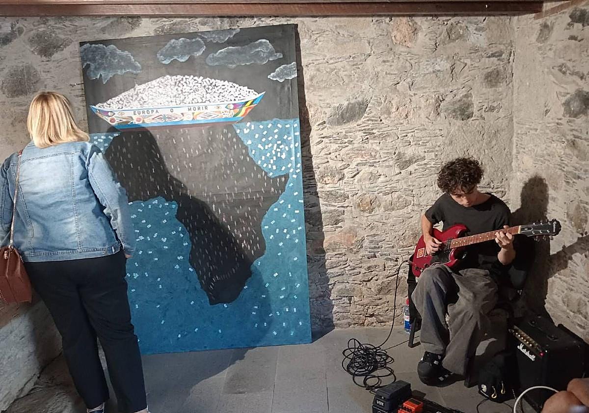 Imagen principal - Víktor Arvín, tocando en la inauguración. Debajo, la concejal de Cultura, Elena Álamo, contemplando el xuadro de Mbaye junto al director del IES, Daniel Escobar. Mbaye hizo cinco de las cuadros de la muestra.