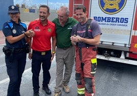 Los bomberos y una policía portuaria sostienen crías de charranes junto a Pascual Calabuig.