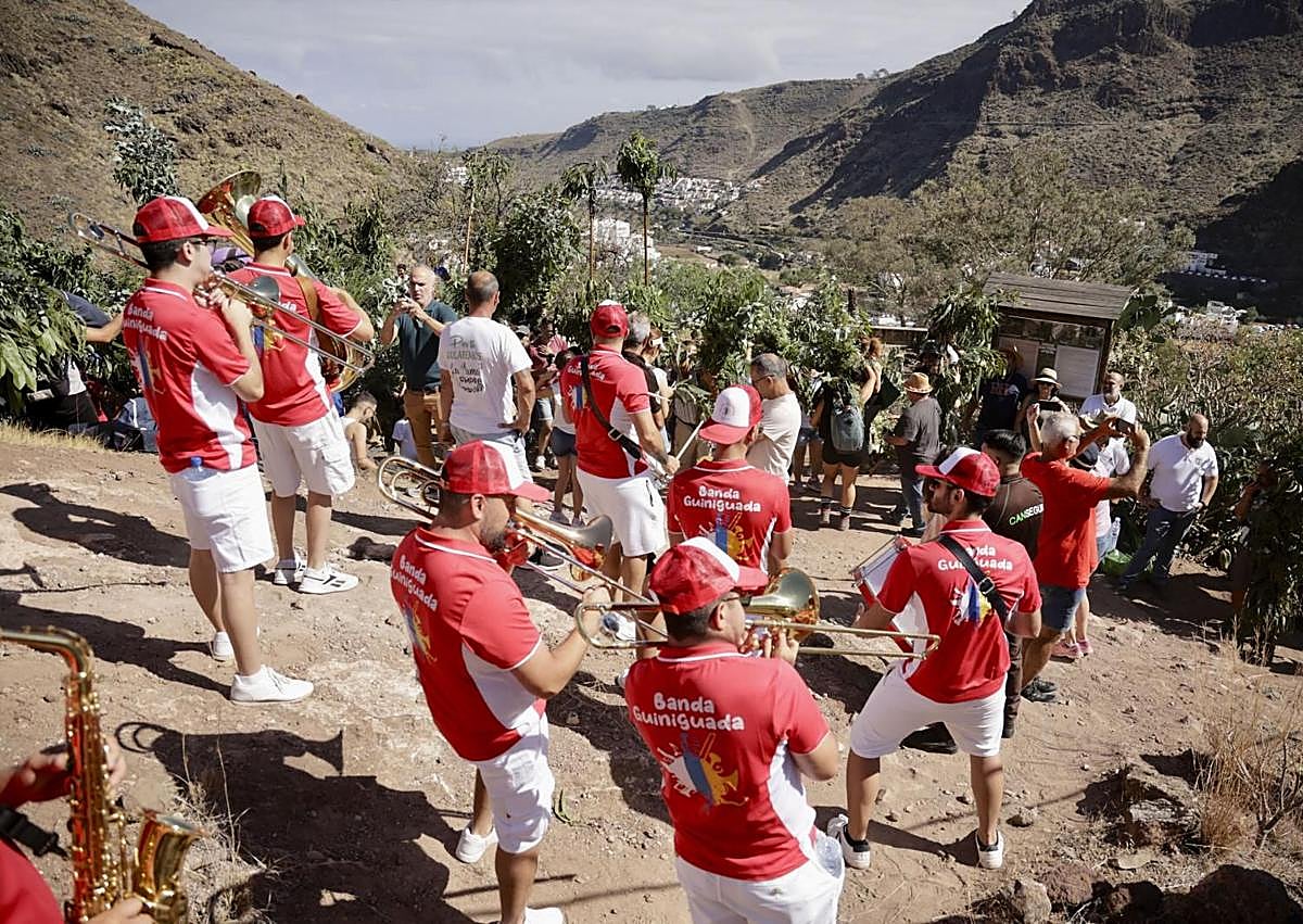 Imagen secundaria 1 - En la foto superior, un romero en mitad de un bosque de ramas. Debajo, la banda Guiniguada, en la Era del Molino, a donde fue a esperar a los romeros, Y al lado, una joven hace sonar un bucio.