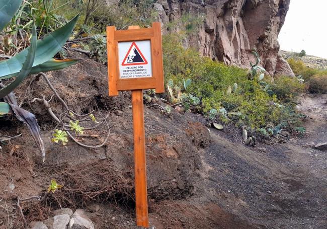 Cartel advirtiendo a los senderistas del riesgo de desprendimientos en un sendero.