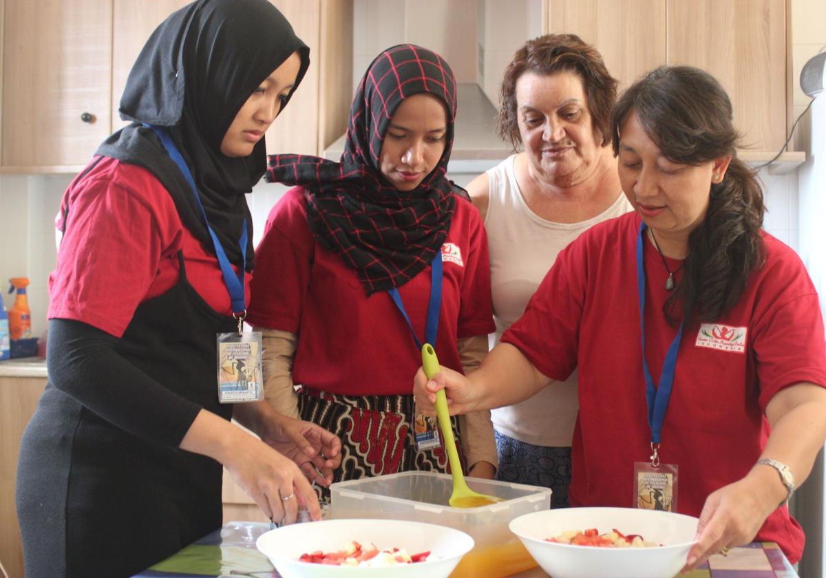 Adela Hernández, en la cocina de su casa, en una edición pasada de las Comidas Interculturales junto a varias participantes del festival.