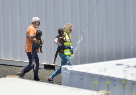 Imagen de archivo de dos trabajadores de los servicios de emergencias con dos niños migrantes que llegaron en una patera a principios de julio a El Hierro.