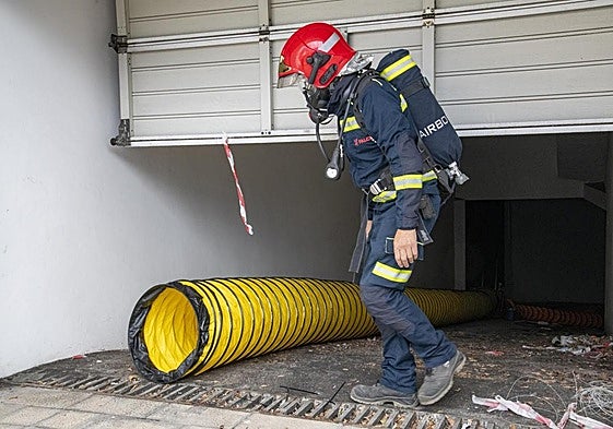 Bombero equipado en labores de mantenimiento en la ventilación de un garaje.