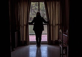 Una víctima de la violencia de género se asoma a la ventana de una casa de acogida para mujeres maltratadas.