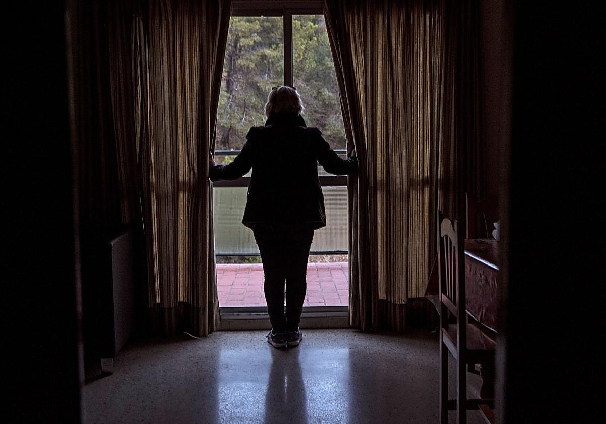 Una víctima de la violencia de género se asoma a la ventana de una casa de acogida para mujeres maltratadas.