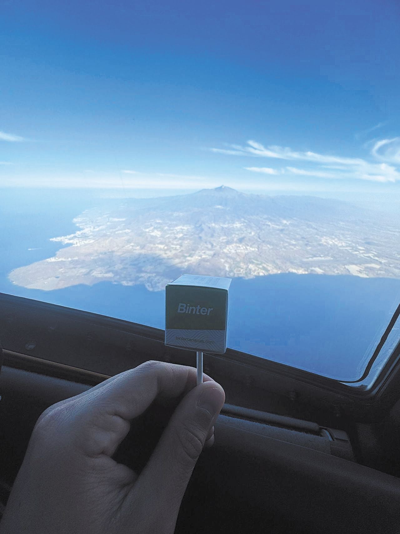 Un pasajero muestra el obsequio especial en apoyo a la inclusión de Binter y Fundación Randstad, con el Teide de fondo.