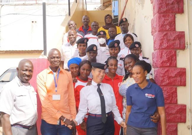 Sonja Arup, en el centro, ataviada de bomebra ak ser reconocida como Bombera Honorífica de Gambia.