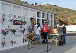 Varios hombres introducen el féretro con los restos del migrante fallecido en un cayuco, en aguas cercanas a El Hierro, el pasado 2024.