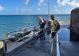 Turistas, esta tarde, alongados en la barandilla del paseo para sortear los charcos