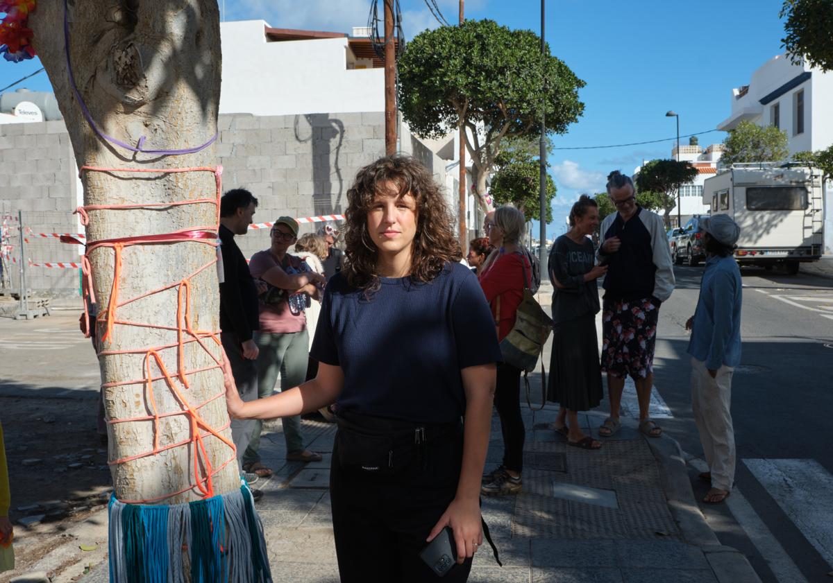 Imagen principal - Arriba, Iris Daute, una de las ciudadanas que pide que se queden los arbolitos donde crecen desde hace veinte años. Abajo, los árboles con la decoración de Tejedoras Subversivas y el ficus Lola, con su historia en español e inglés.