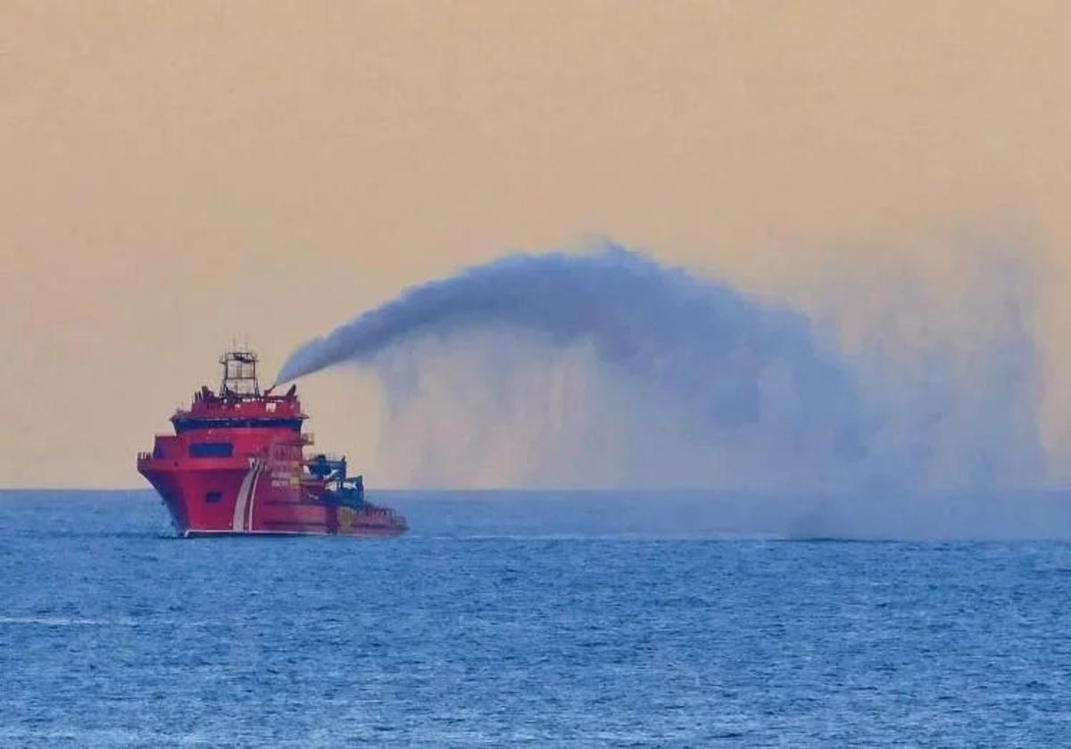 Imagen de la embarcación de Salvamento Marítimo apagando las llamas del pesquero incendiado frente a la costa de Telde.