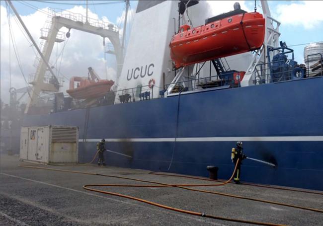 Bomberos intentando apagar el incendio antes de que el barco se sacara del puerto.