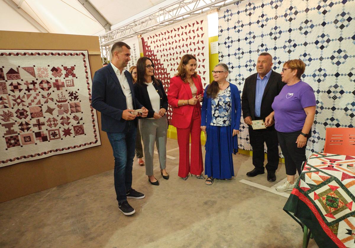 La presidenta Lola García y el alcalde Matías Peña, entre otros, arropan a la Premio Insular 2025, Bianca Spartari, en su expositor donde cuelgan sus trabajos en tela.