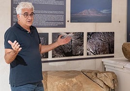 Valentín Barroso, director de Arqueocanaria, en el ciclo Entre Vitrinas del Museo Arqueológico de Fuerteventura, al lado de un panel de podomorfos.