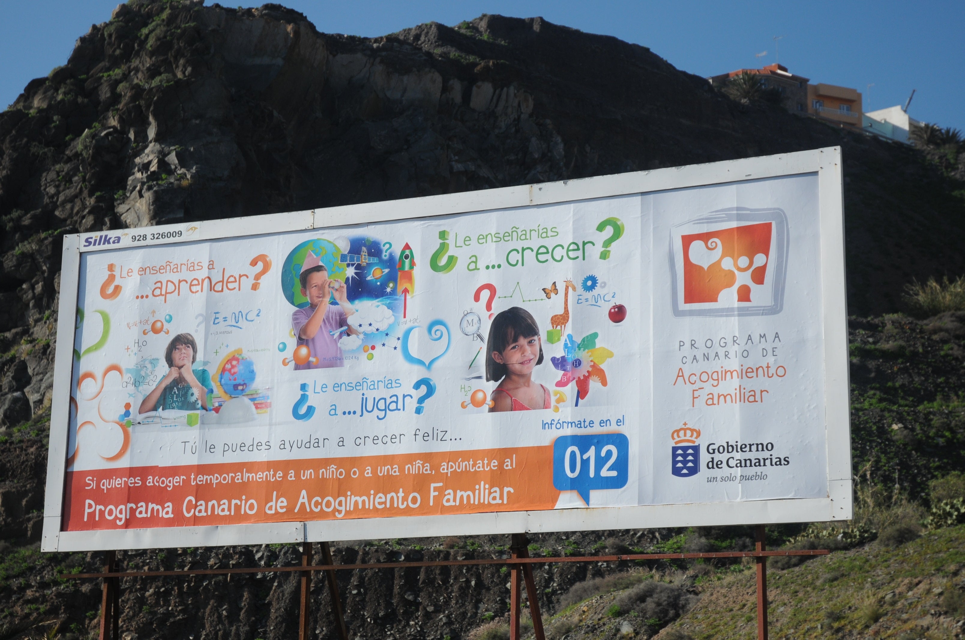 Foto de 2013 de una valla informando del progama canario de acogimiento familiar.