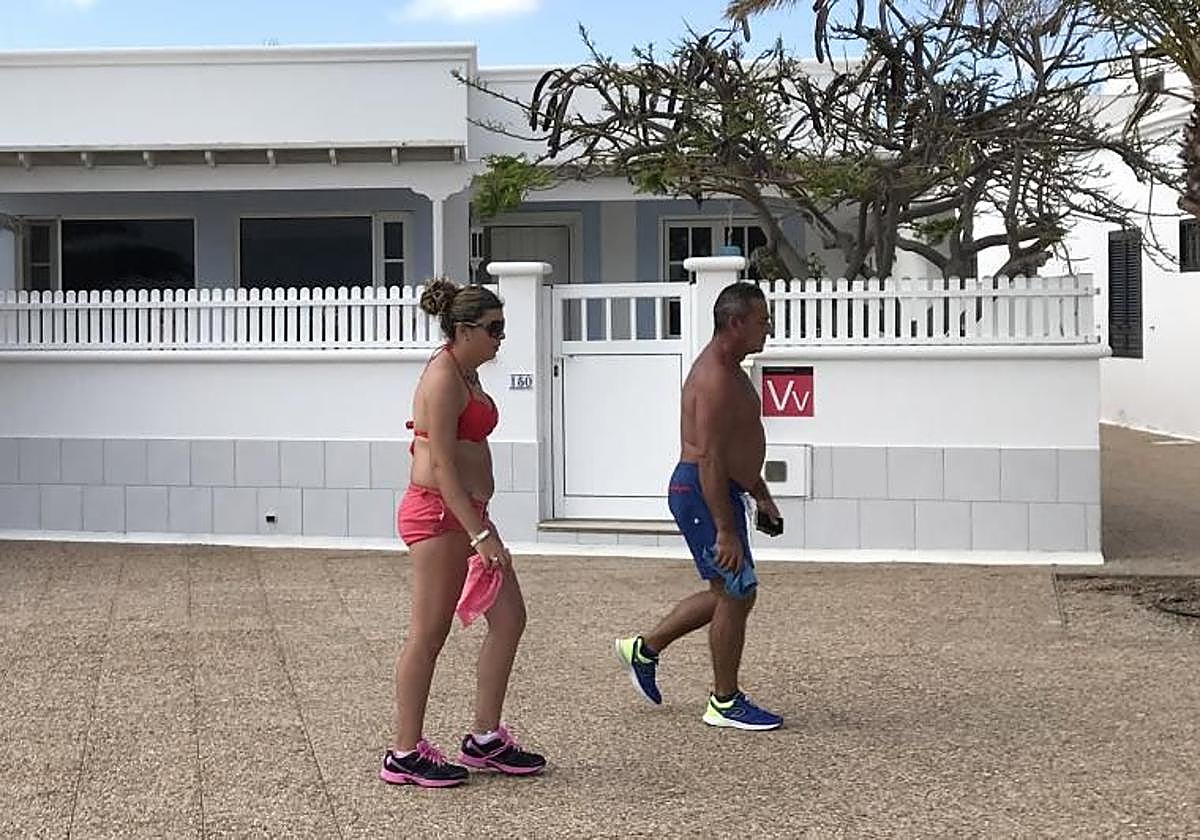 Dos turistas caminan por delante de una vivienda vacacional en Lanzarote.