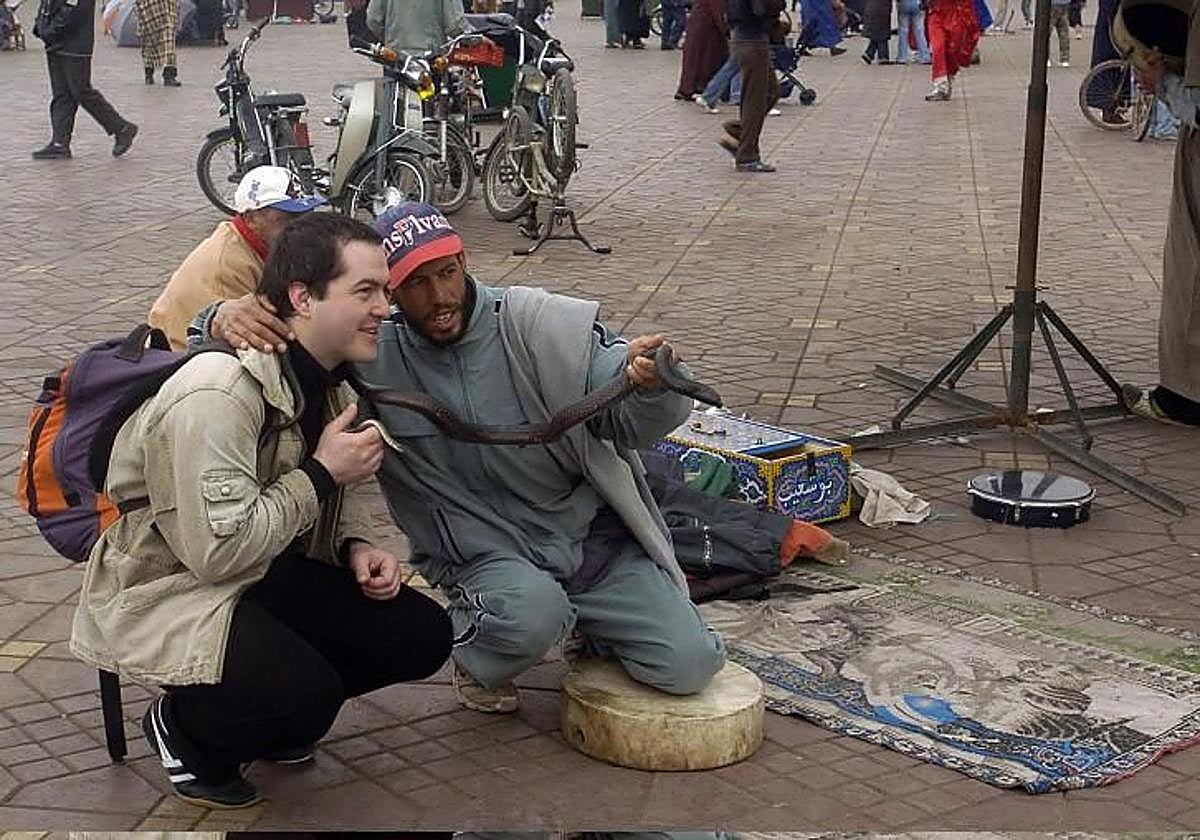 Un encantador de serpientes con un turista en la plaza Jemaa el-Fna de Marrakech.