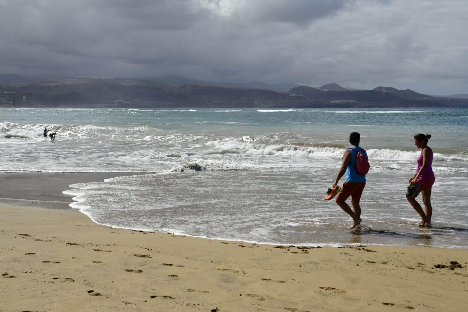 Gente paseando por la orilla de laplaya de Las Canteras.