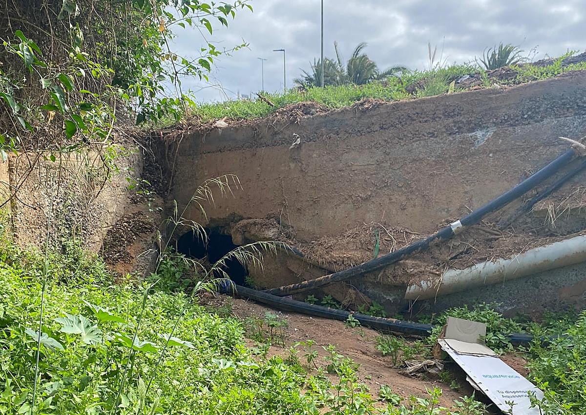Imagen secundaria 1 - En la foto superior, canalización del barranco de Sacateclas saliendo de Las Huesas, y en la foto inferior izquierda, embudo por el que pretenden que se metan sus aguas. La consecuencia se observa en la tercera imagen. La escorrentía usó la GC-117 bajo la GC-1 como canal de paso. La mancha del barro deja ver hasta qué altura llegó. 
